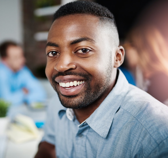Smiling man in blue shirt at professional orthodontics office gathering or event.