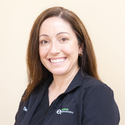 Professional headshot of smiling female orthodontist wearing dark polo shirt with Elvebak Orthodontics logo.