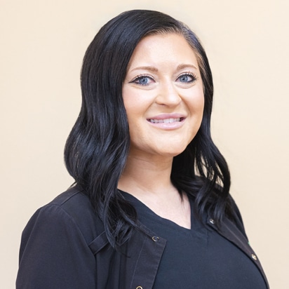 Professional headshot of smiling woman with long dark hair wearing black shirt against neutral background.