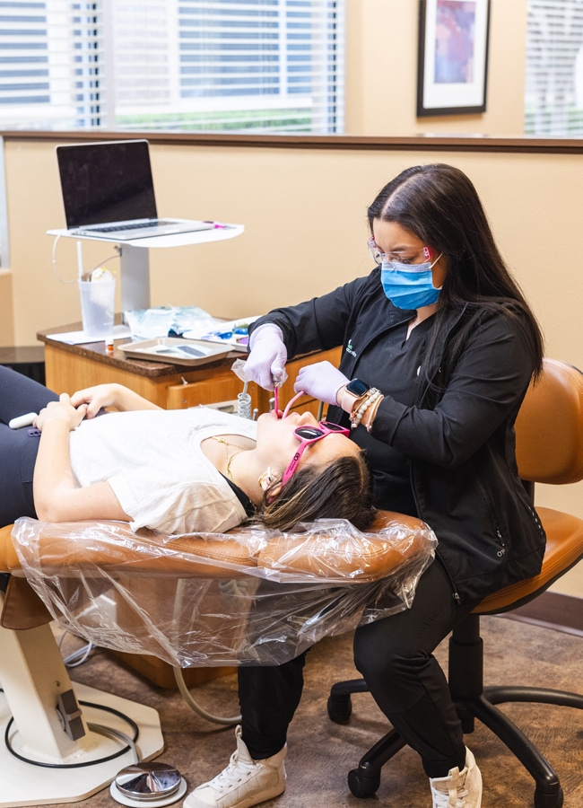 Patient receiving orthodontic treatment with a dental assistant at Elvebak Orthodontics in Plano, TX.