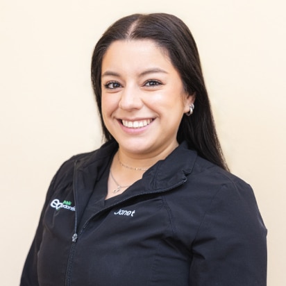 Professional headshot of smiling woman in dark Elvebak Orthodontics branded jacket against neutral background.