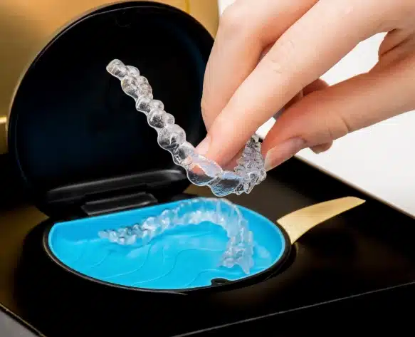 Teen patient holding Invisalign clear aligners at Elvebak Orthodontics in Plano, TX.