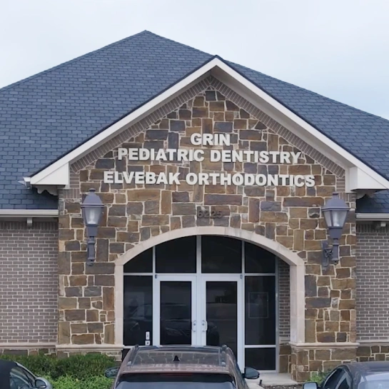 Exterior of Grin Pediatric Dentistry and Elvebak Orthodontics brick building with entrance.