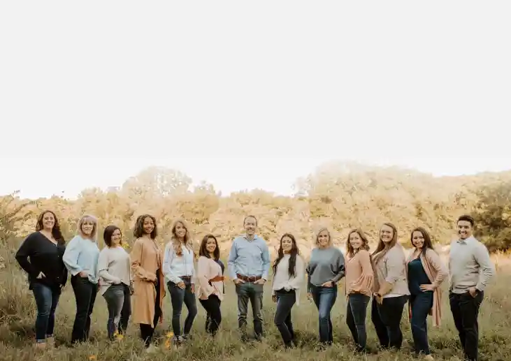 Large group of people standing together in a field wearing casual clothing.